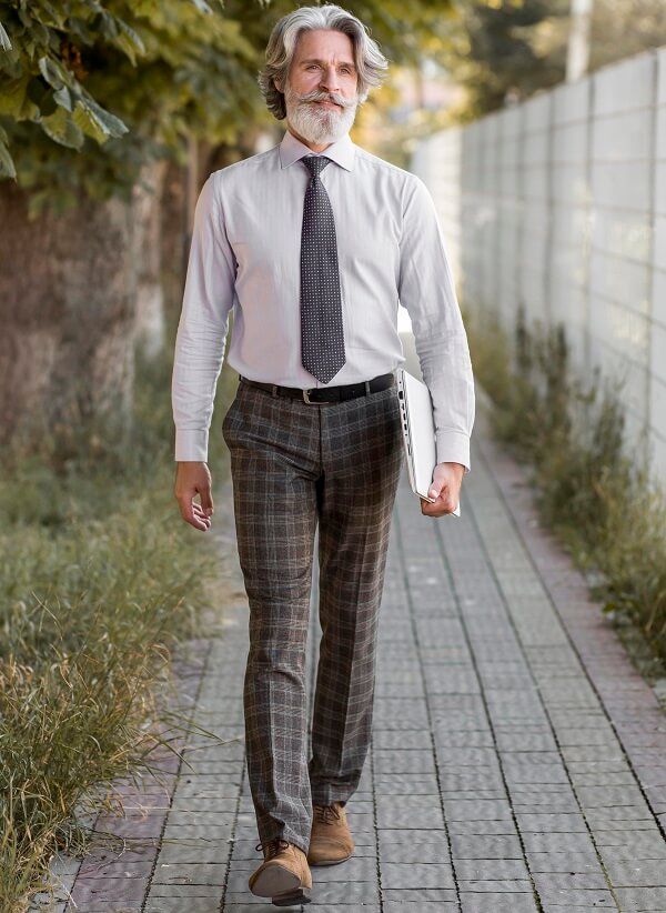 Man wearing a white shirt and tie, paired with plaid pants and suede boots.